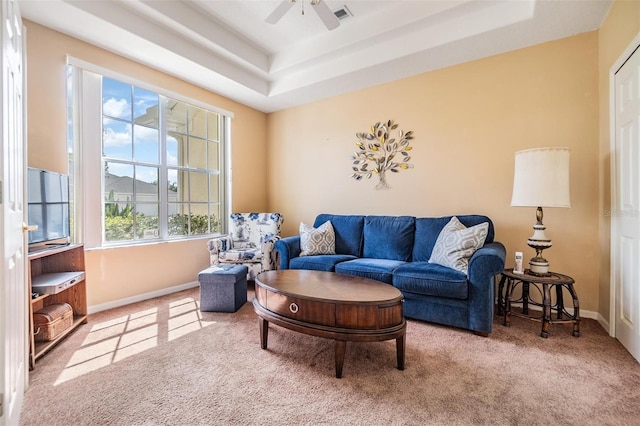 living room featuring a tray ceiling, ceiling fan, and carpet