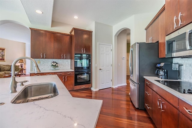 kitchen featuring backsplash, black appliances, dark hardwood / wood-style flooring, sink, and light stone countertops