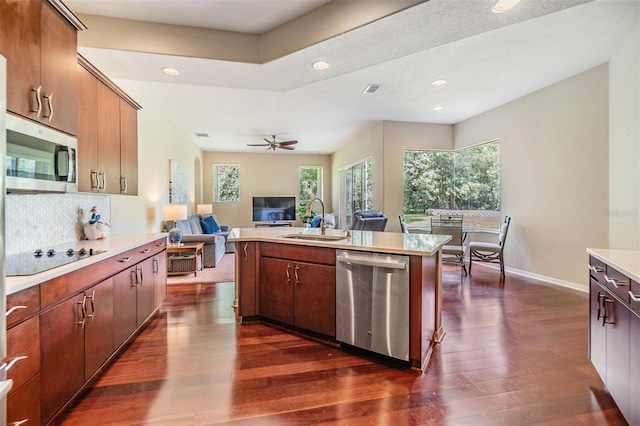 kitchen featuring backsplash, appliances with stainless steel finishes, sink, dark hardwood / wood-style floors, and an island with sink