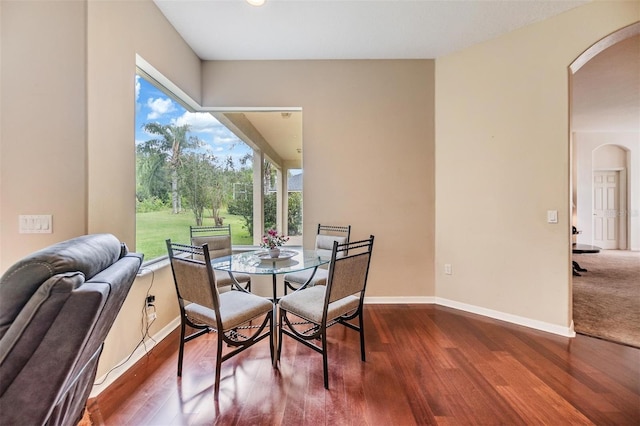 dining room with baseboards, arched walkways, and wood finished floors