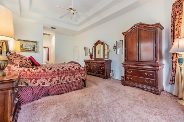 bedroom featuring carpet floors, visible vents, a tray ceiling, and ceiling fan