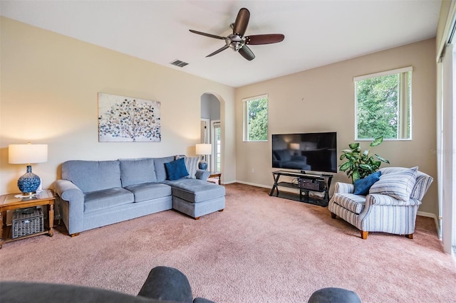 carpeted living area with ceiling fan, visible vents, arched walkways, and a wealth of natural light