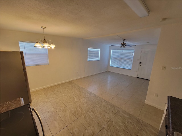 unfurnished dining area featuring light tile patterned floors, a textured ceiling, baseboards, and ceiling fan with notable chandelier