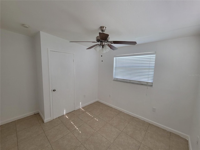 spare room featuring light tile patterned floors, ceiling fan, and baseboards