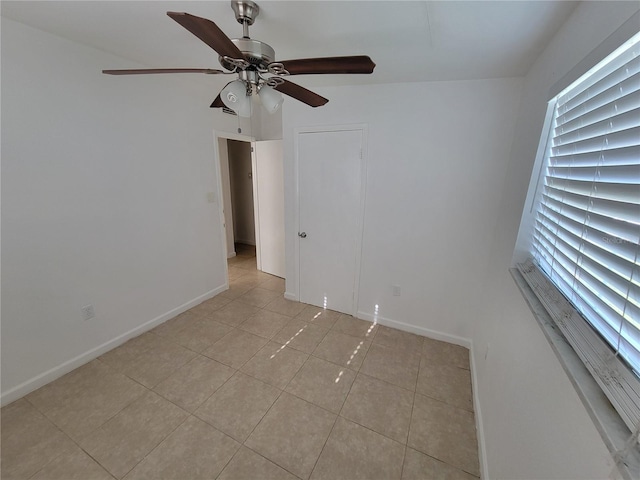 empty room featuring light tile patterned floors, plenty of natural light, and baseboards