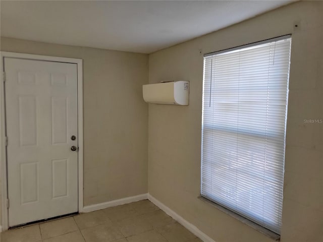 empty room featuring light tile patterned floors, an AC wall unit, and baseboards