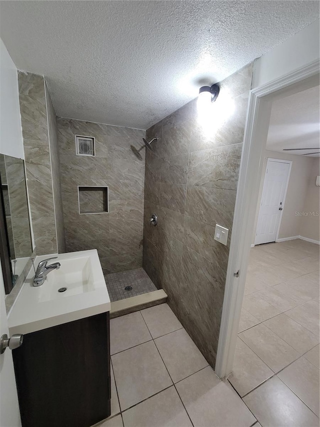 bathroom with a stall shower, vanity, a textured ceiling, and tile patterned floors