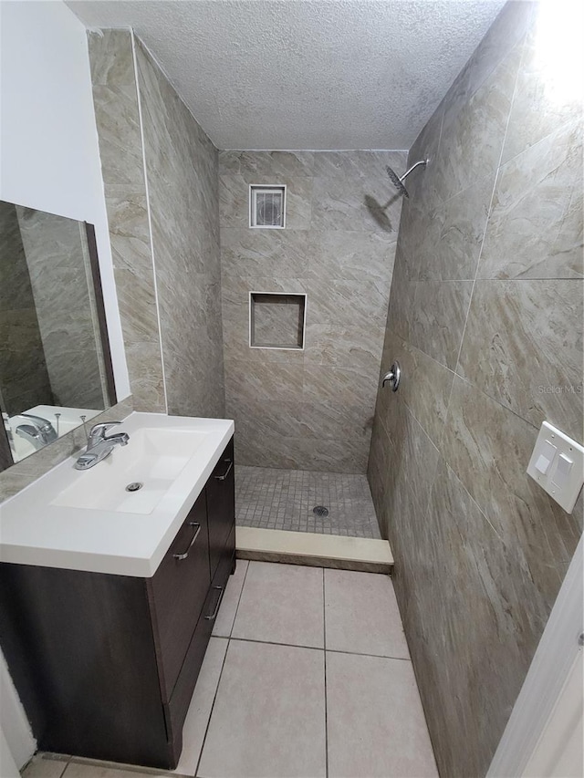 bathroom with a stall shower, vanity, a textured ceiling, and tile patterned floors