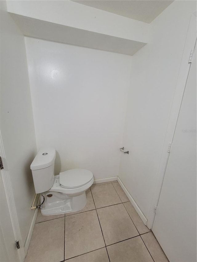 half bath featuring toilet, tile patterned flooring, and baseboards