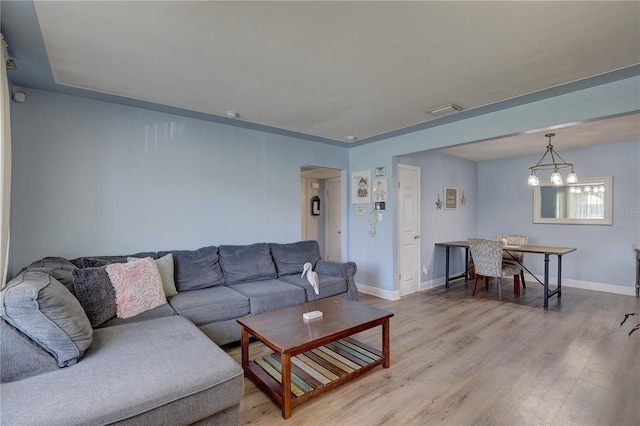 living room featuring a chandelier and light wood-type flooring