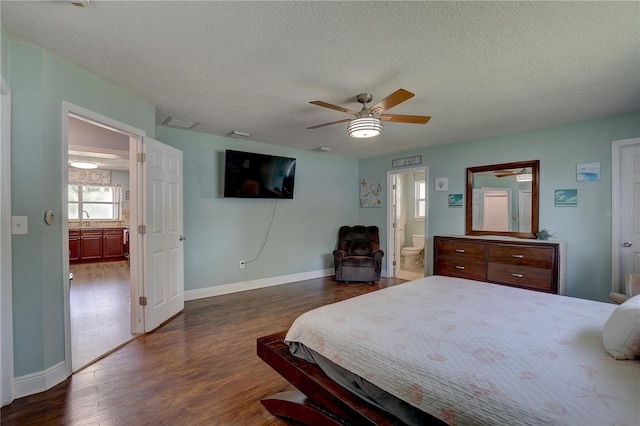 bedroom with ensuite bath, ceiling fan, sink, dark hardwood / wood-style flooring, and a textured ceiling