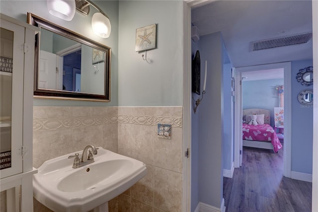 bathroom featuring sink, wood-type flooring, and tile walls