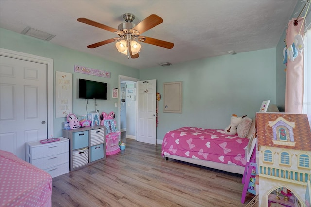 bedroom with a closet, light hardwood / wood-style floors, and ceiling fan