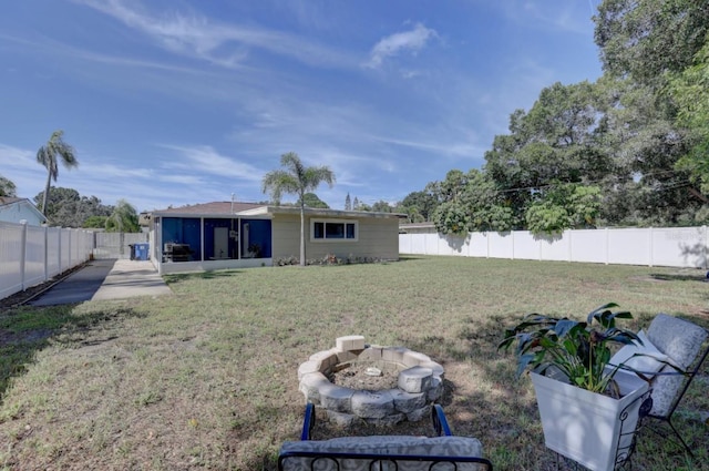 rear view of house featuring a fire pit, a sunroom, and a lawn