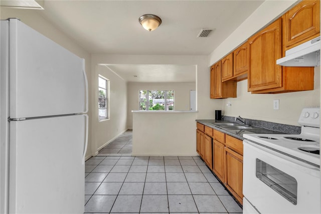 kitchen featuring sink, light tile patterned flooring, and white appliances