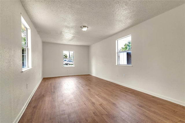 unfurnished room with hardwood / wood-style flooring, a textured ceiling, and a healthy amount of sunlight