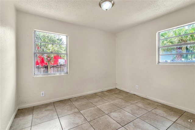 unfurnished room featuring light tile patterned flooring, a textured ceiling, and a healthy amount of sunlight