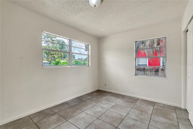 unfurnished room featuring a textured ceiling and tile patterned floors