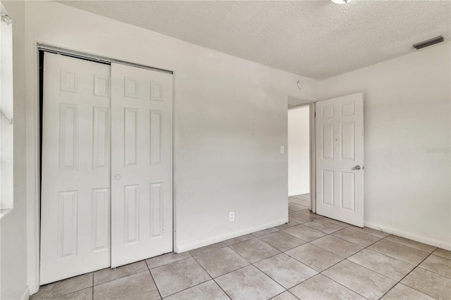 unfurnished bedroom featuring light tile patterned floors, a closet, and a textured ceiling