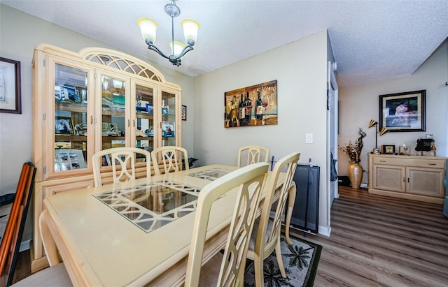 dining area with a notable chandelier, a textured ceiling, and wood finished floors