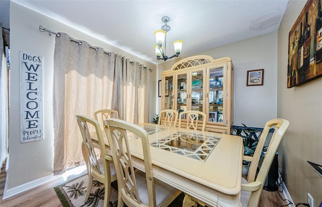 dining area with baseboards, an inviting chandelier, and wood finished floors