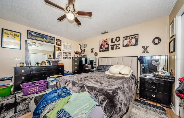 bedroom with ceiling fan, hardwood / wood-style flooring, and a textured ceiling