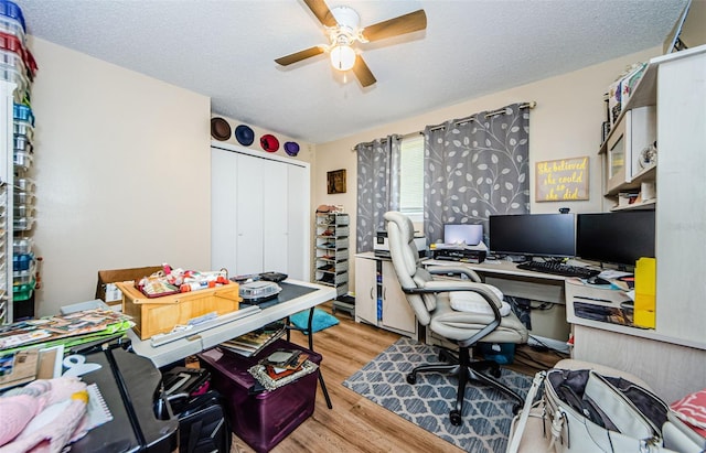 home office featuring light wood-type flooring, a textured ceiling, and ceiling fan