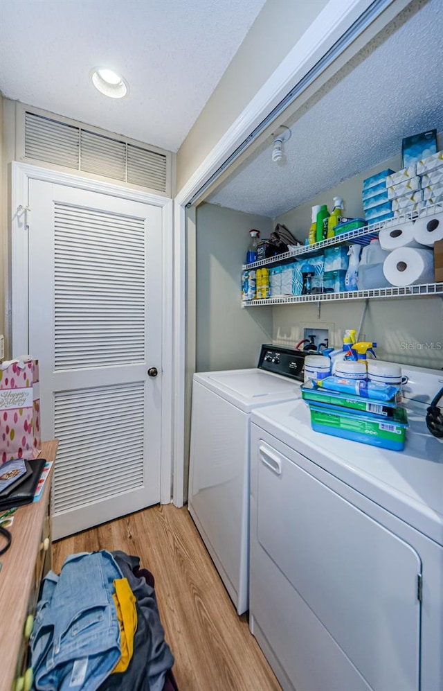 laundry area with washing machine and dryer, light wood-style flooring, and a textured ceiling