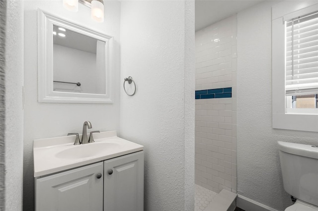 bathroom with vanity, a tile shower, and toilet