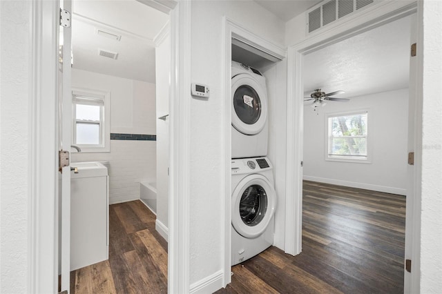 clothes washing area with ceiling fan, stacked washer and clothes dryer, and dark hardwood / wood-style floors