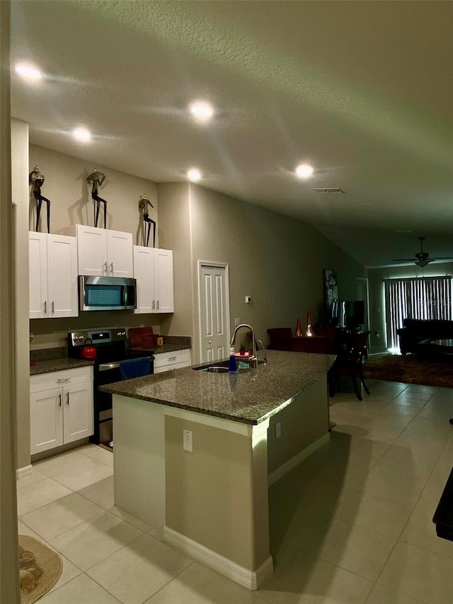 kitchen with black / electric stove, a kitchen island with sink, sink, and white cabinets