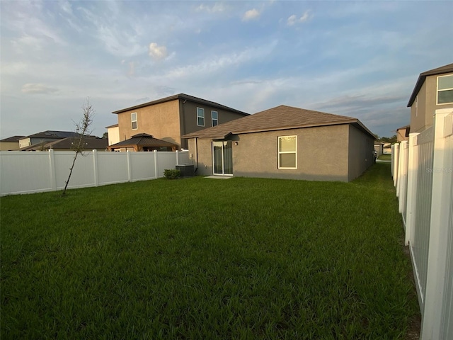 rear view of property featuring a yard and fence