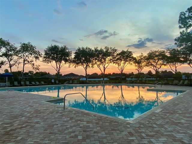 pool at dusk featuring a patio