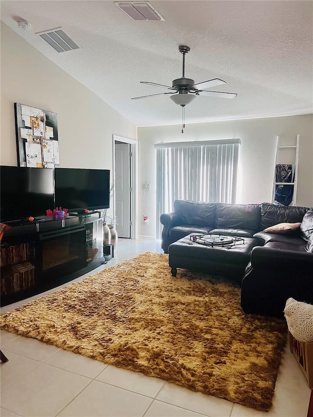 tiled living area with lofted ceiling, a textured ceiling, visible vents, and a ceiling fan