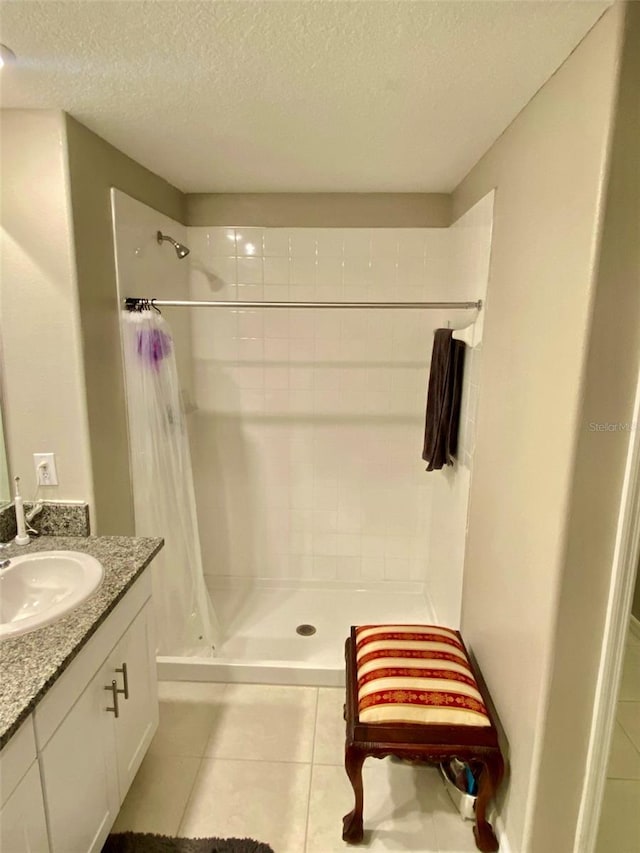 bathroom featuring a textured ceiling, a stall shower, vanity, and tile patterned floors