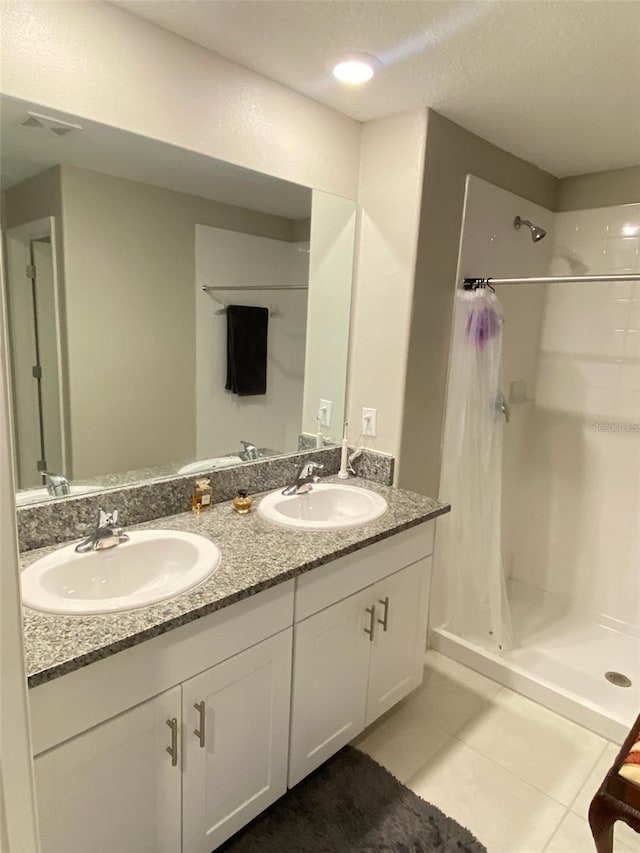 bathroom featuring double vanity, tile patterned flooring, a sink, and a shower stall