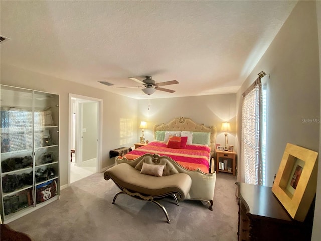 carpeted bedroom with a textured ceiling, ceiling fan, and visible vents