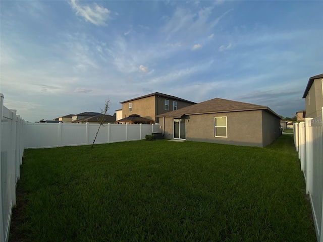 exterior space featuring a fenced backyard, a lawn, and stucco siding