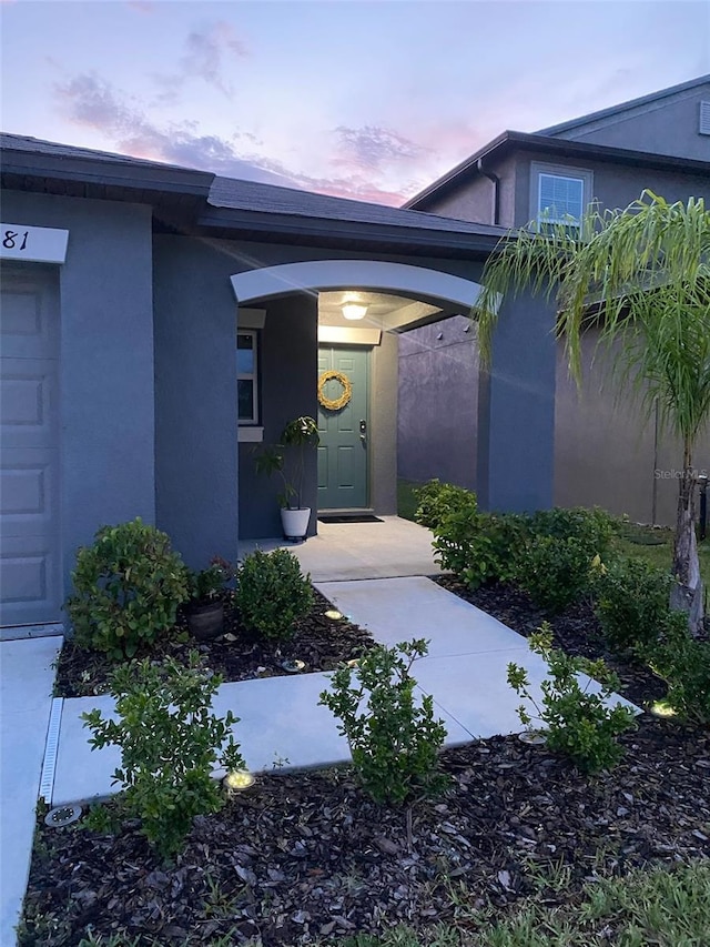 doorway to property with a garage and stucco siding