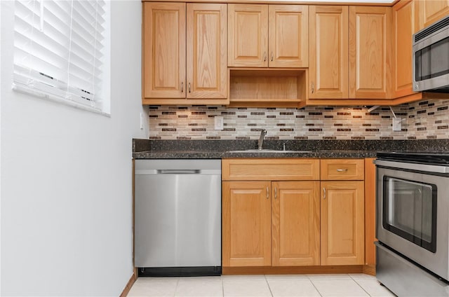 kitchen featuring dark stone countertops, stainless steel appliances, sink, light tile patterned flooring, and tasteful backsplash