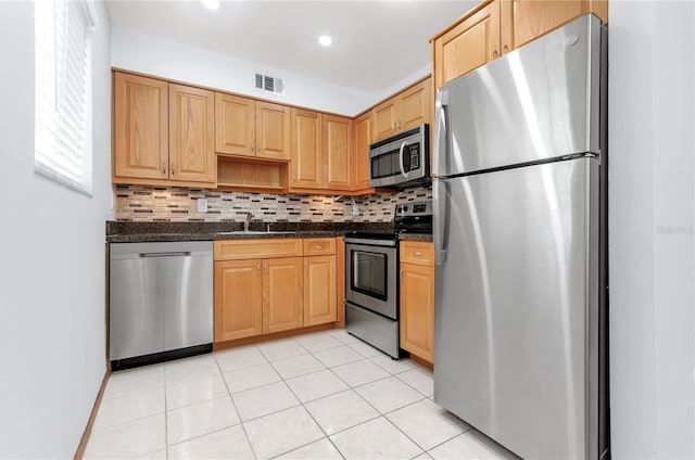 kitchen with dark stone countertops, stainless steel appliances, light tile patterned flooring, and decorative backsplash