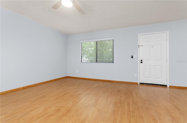 spare room with a textured ceiling, ceiling fan, and light hardwood / wood-style floors