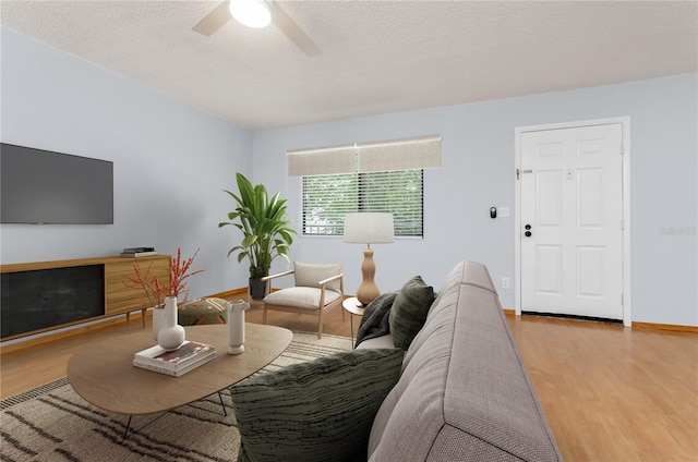 living room with ceiling fan, light hardwood / wood-style floors, and a textured ceiling