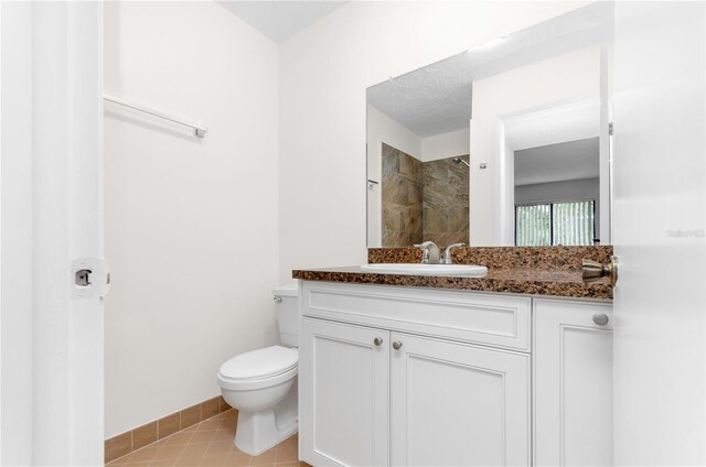 bathroom featuring a textured ceiling, vanity, walk in shower, tile patterned flooring, and toilet