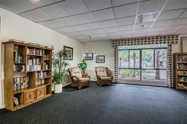 living area with a paneled ceiling, carpet flooring, and a baseboard heating unit