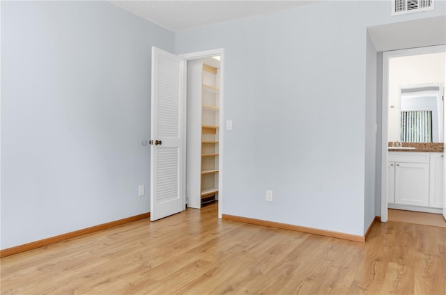 unfurnished bedroom with light hardwood / wood-style floors and sink