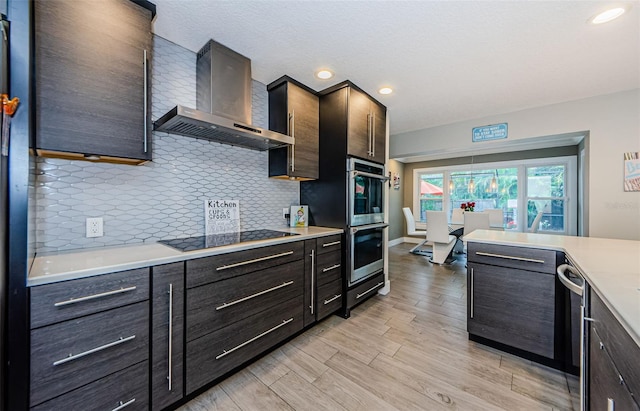 kitchen with light hardwood / wood-style floors, backsplash, stainless steel appliances, and wall chimney range hood