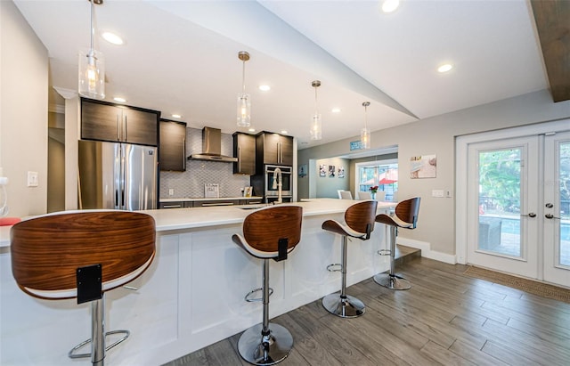 kitchen with hardwood / wood-style floors, stainless steel refrigerator, lofted ceiling, wall chimney exhaust hood, and tasteful backsplash