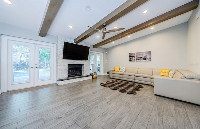 living room featuring a fireplace, lofted ceiling with beams, a healthy amount of sunlight, light hardwood / wood-style flooring, and ceiling fan