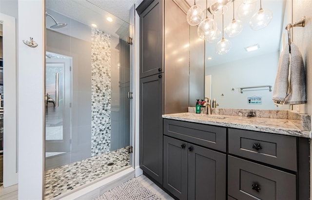 bathroom featuring tile patterned flooring, a shower with door, a textured ceiling, and vanity